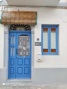 eine blaue Tür und Fenster auf einem weißen Gebäude in der Unterkunft Arzella Holiday Home in Birżebbuġa