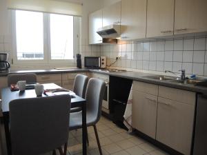 eine Küche mit einem Tisch, Stühlen und einem Waschbecken in der Unterkunft Moderne Monteurwohnung mit Dachterrasse für 4 Personen in Schipkau
