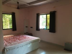une chambre avec un lit et deux fenêtres dans l'établissement Misty Woods Eco Cottages, à Harihareshwar