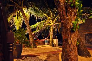 two palm trees with a hammock between them at La Veranda Di Serena in Unawatuna