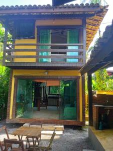 ein Haus mit einer Terrasse mit Tisch und Stühlen in der Unterkunft Condominio Village Camburi in Camburi