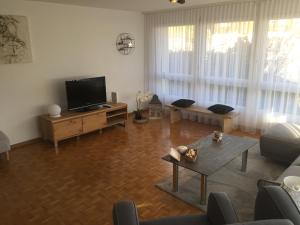 ein Wohnzimmer mit einem Flachbild-TV und einem Tisch in der Unterkunft Lake View Apartment in Faulensee