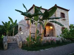 a stone house with a palm tree in front of it at Stoupa's Paradise in Stoupa