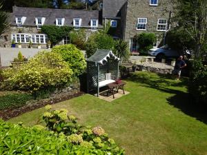 a man standing in a garden with a gazebo at Yr Hen Felin - The Old Mill B&B in Morfa Nefyn