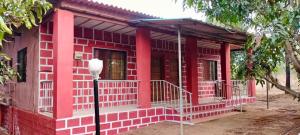 une maison rouge avec une véranda et un éclairage de rue dans l'établissement Misty Woods Eco Cottages, à Harihareshwar 3 autres photos