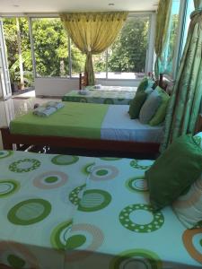 two beds in a bedroom with green and blue sheets at Hospedaje casa Lucía in Leticia