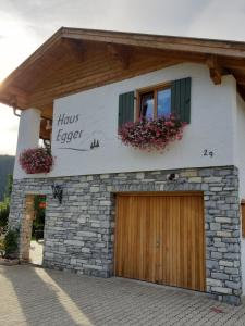 a building with a door and two windows and flowers at Haus Egger in Reit im Winkl