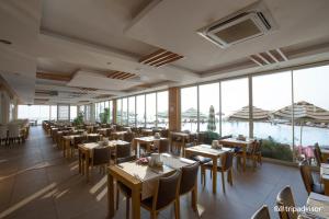 a dining room with tables and chairs and windows at gold city alanya appartement in Kargicak