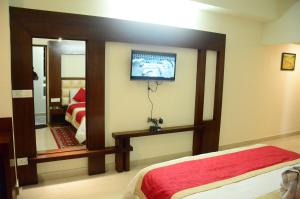 a bedroom with a bed and a tv on the wall at Hotel Milam Inn in Almora