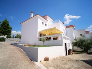 a white house with a yellow umbrella on a street at Sithonia Lodge in Metamorfosi