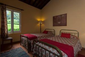 una camera con due letti con cuscini rossi e una finestra di Lake Cottage - Panoramic views 7 Cidades a Sete Cidades