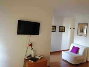ein Wohnzimmer mit einem weißen Stuhl und einem Flachbild-TV in der Unterkunft Studio Telheiras 2 in Lissabon