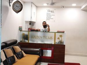 un hombre parado detrás de un mostrador en un salón en Hotel Golden Palms en Bombay