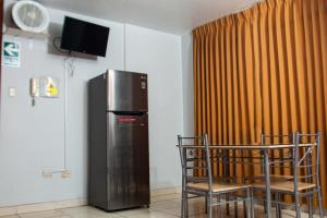 a room with a refrigerator and two chairs and a television at Hostal Vasco in Tacna