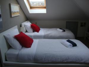 two beds with red and white pillows in a room at Valckesteyn in Poortugaal