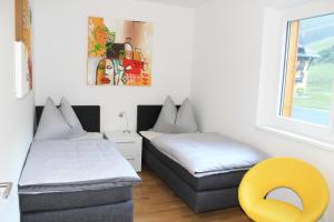 a room with two beds and a yellow chair at Ferienapartment Nassfeld in Sonnenalpe Nassfeld