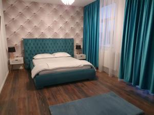 Schlafzimmer mit einem Bett mit blauem Kopfteil und blauen Vorhängen in der Unterkunft GARSONIERRE CENTRAL LUXURY in Târgu Jiu