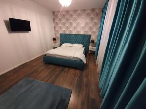 niewielka sypialnia z łóżkiem z niebieskim zagłówkiem w obiekcie GARSONIERRE CENTRAL LUXURY w mieście Târgu Jiu