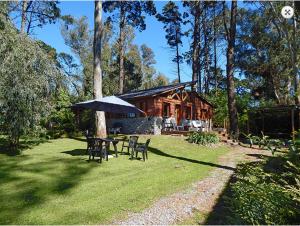 Cabaña de madera con mesa, sillas y sombrilla en Cabañas Altos del Bosque en Mar del Plata