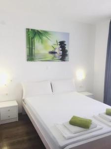 a bedroom with a white bed with a painting on the wall at Delfin Apartments in Crikvenica