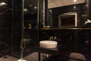 a black bathroom with a sink and a shower at The Chesterton Hotel in Bicester