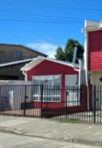 a red house with a fence in front of it at Departamentos Egaña in Puerto Montt