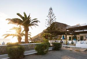 a restaurant on the beach with palm trees and the ocean at Glaros luxury studio on the Beach in Arkasa
