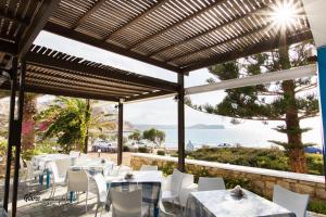 a restaurant with white tables and chairs and the ocean at Glaros luxury studio on the Beach in Arkasa