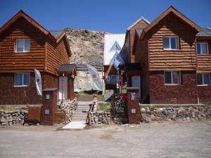 a group of wooden homes with a sign in front of them at Aparthotel Aldea Termal in Copahue