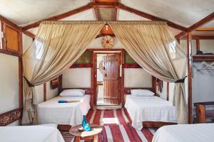 a room with two beds with curtains and a table at Talist Siwa in Siwa