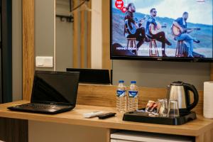 a laptop on a desk with a tv and water bottles at Hayat Palas in Erzincan