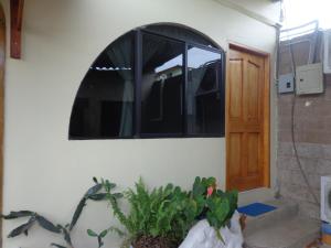una puerta a una habitación con una ventana y una planta en Hostal Nathaly en Puerto Baquerizo Moreno