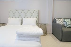 a bedroom with a white bed with a chair and pillows at Comfy Studio 7 by ReCharge in Singapore