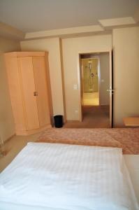 a bedroom with a white bed and a bathroom at Hotel Cafe Leda in Haigerloch