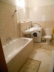 a bathroom with a tub and a sink and a washing machine at La Perla Wellness Apartman in Siófok
