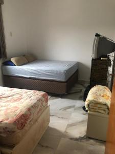 1 dormitorio con 2 camas y TV. en Cantinho da Lu em apt inteiro 800 mt da praia en Bertioga