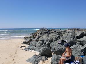 a woman sitting on a beach holding a fishing pole at Blue Ocean in Moliets-et-Maa