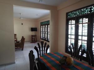 a dining room with a table and chairs and windows at Ceylon Epic Inn in Bentota