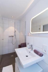 ein weißes Badezimmer mit Waschbecken und Spiegel in der Unterkunft Appartement Neuenstadt in ruhiger Lage im Wohngebiet in Neuenstadt am Kocher