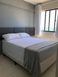 a bedroom with a white bed with a window at Apartamento 02 quartos completo, BEIRA-MAR com piscina in Maceió