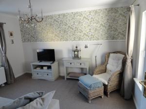 a living room with a tv and a chair and a table at Cottage Ferienwohnung mit Seeblick in Caputh