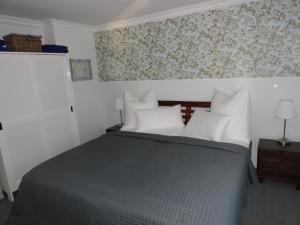 Schlafzimmer mit einem Bett mit weißen Kissen und Tapeten in der Unterkunft Cottage Ferienwohnung mit Seeblick in Caputh