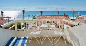 uma varanda com uma mesa e cadeiras e o oceano em BeachFront Rooms Marina di Ragusa em Marina di Ragusa