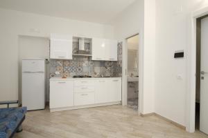 Biała kuchnia z białymi szafkami i drewnianą podłogą w obiekcie Residence La Conchiglia w mieście Vieste