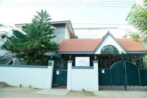 dom z czarną bramą i białym płotem w obiekcie ZuriEL Suite GUEST HOUSE w mieście Coimbatore