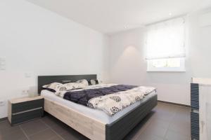 ein Schlafzimmer mit einem großen Bett in einem weißen Raum in der Unterkunft Appartement Neuenstadt in ruhiger Lage im Wohngebiet in Neuenstadt am Kocher