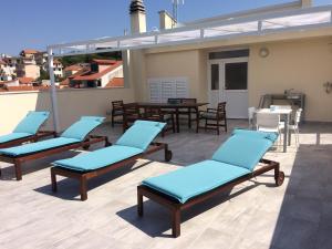 a patio with blue chairs and tables on a roof at Apartments Ivan Zaton in Zaton