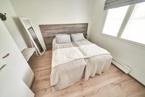 a white bedroom with a bed and a window at Apartments Huili in Tahkovuori