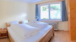 una camera da letto con un grande letto bianco con una finestra di Relax - Haus Swiss a Grächen