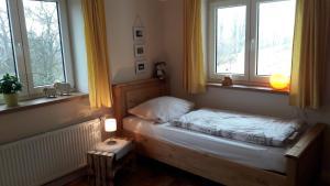 Cama pequeña en habitación con 2 ventanas en Ferienhof Moosing, en Amtzell